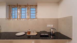 A kitchen with a black countertop, a window with wooden frames, a kettle, a scale, and a plate. - Infinity stays (Puducherry)