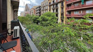 Ένα πολυώροφο κτίριο κατοικιών με πολλά μπαλκόνια, θέα στον δρόμο και δέντρα στο προσκήνιο.