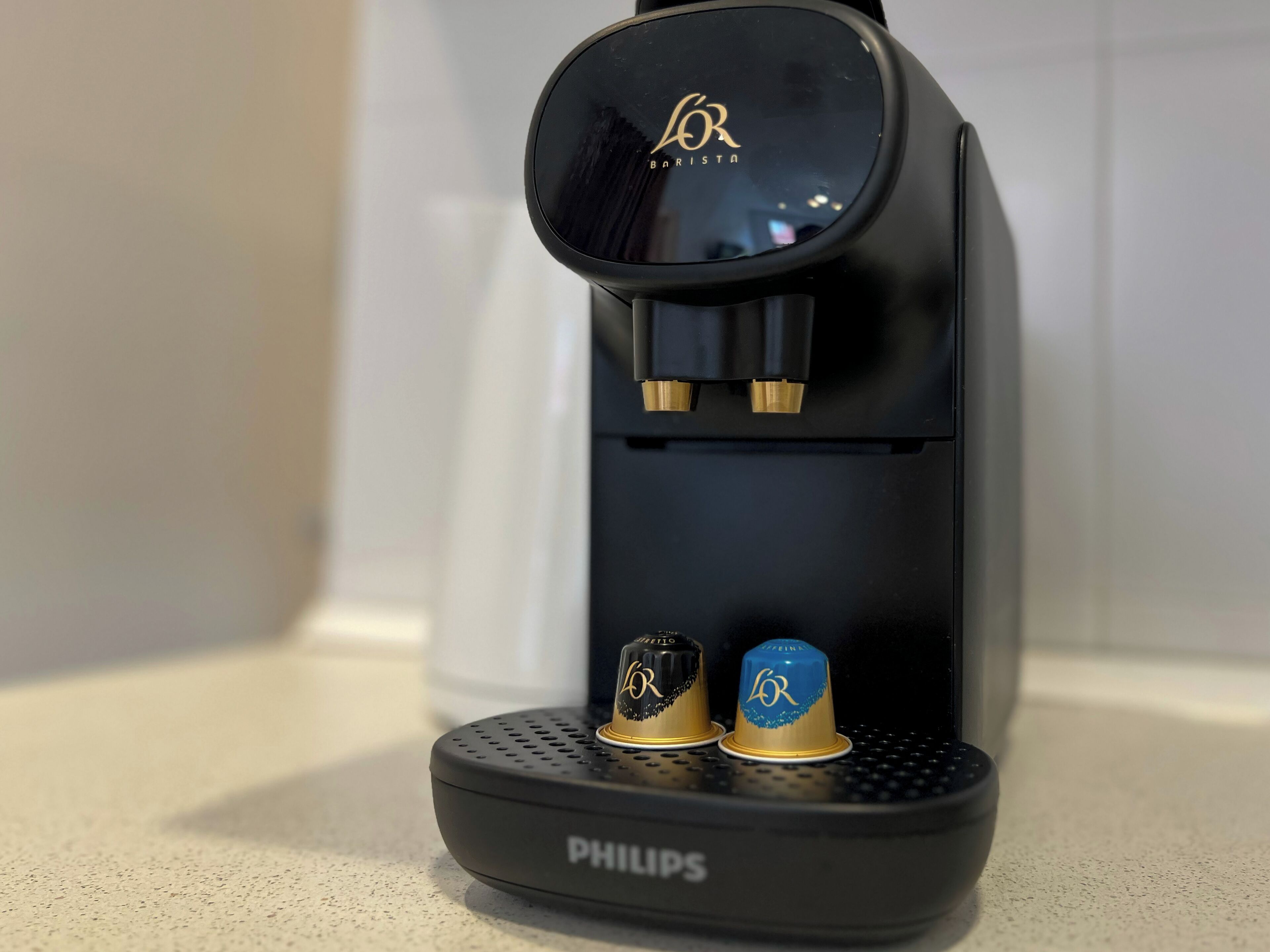 A black Philips coffee maker with two gold and one blue coffee pod holder.