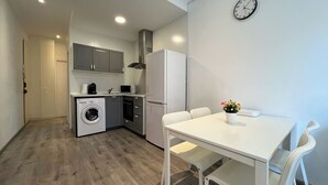 Μια μικρή, λειτουργική κουζίνα με πλυντήριο ρούχων, φούρνο μικροκυμάτων και ψυγείο.