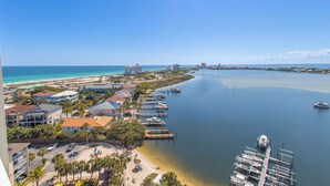 A coastal marina with boats, a beach, and buildings along the shore.