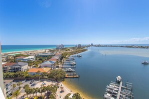 A coastal marina with boats, a beach, and buildings along the shore.