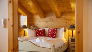 A wooden-paneled bedroom with a bed, pillows, bedside lamps, and a nightstand. - Chalet Chafrebelle - sauna & view (Haute-Nendaz)