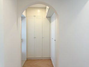 Stylish hallway with a double-door closet and mirrored door, set against a backdrop of herringbone flooring.