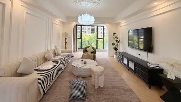 A spacious living room with a sofa, coffee table, and TV.