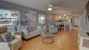 A spacious living room with a sofa, armchairs, and a glass coffee table. A dining area with a table and chairs is visible in the background. - 119 El Matador 2 Bedroom Condo (Fort Walton Beach)