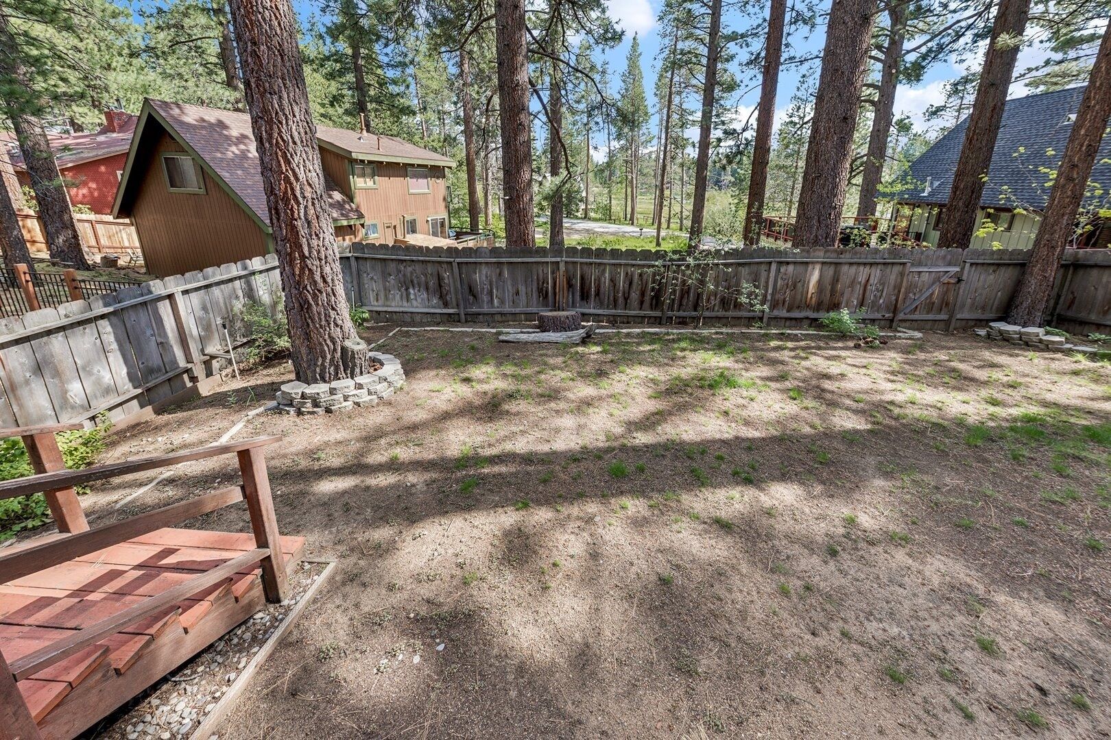 A backyard with a wooden deck, a small wooden structure, and a fenced area.