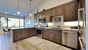 A modern kitchen with wooden cabinets, stainless steel appliances, and pendant lighting. - 1849 Condos 642 3 Bedroom Home (Mammoth Lakes)