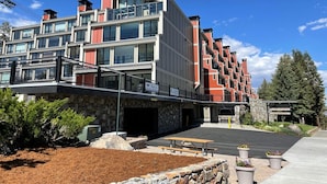 A multi-story hotel with a modern architectural design, featuring balconies, a covered entrance, and a landscaped outdoor area with a picnic table. - 1849 Condos 642 3 Bedroom Home (Mammoth Lakes)