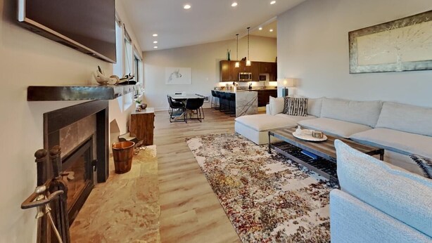 A modern living room with a fireplace, a dining area, and a kitchen in the background. - 1849 Condos 642 3 Bedroom Home (Mammoth Lakes)