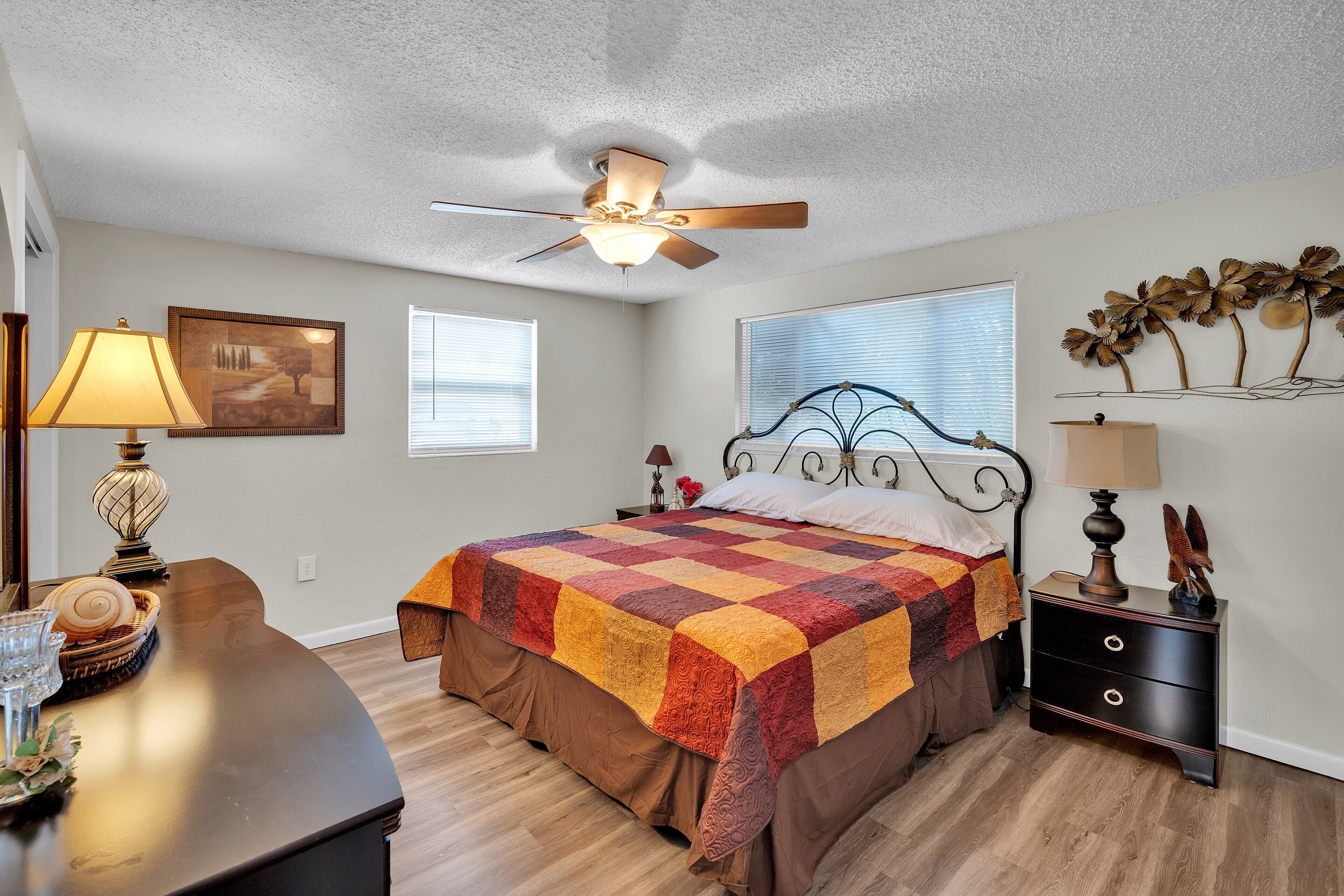 A bedroom with a bed, a nightstand, a desk, and a ceiling fan.