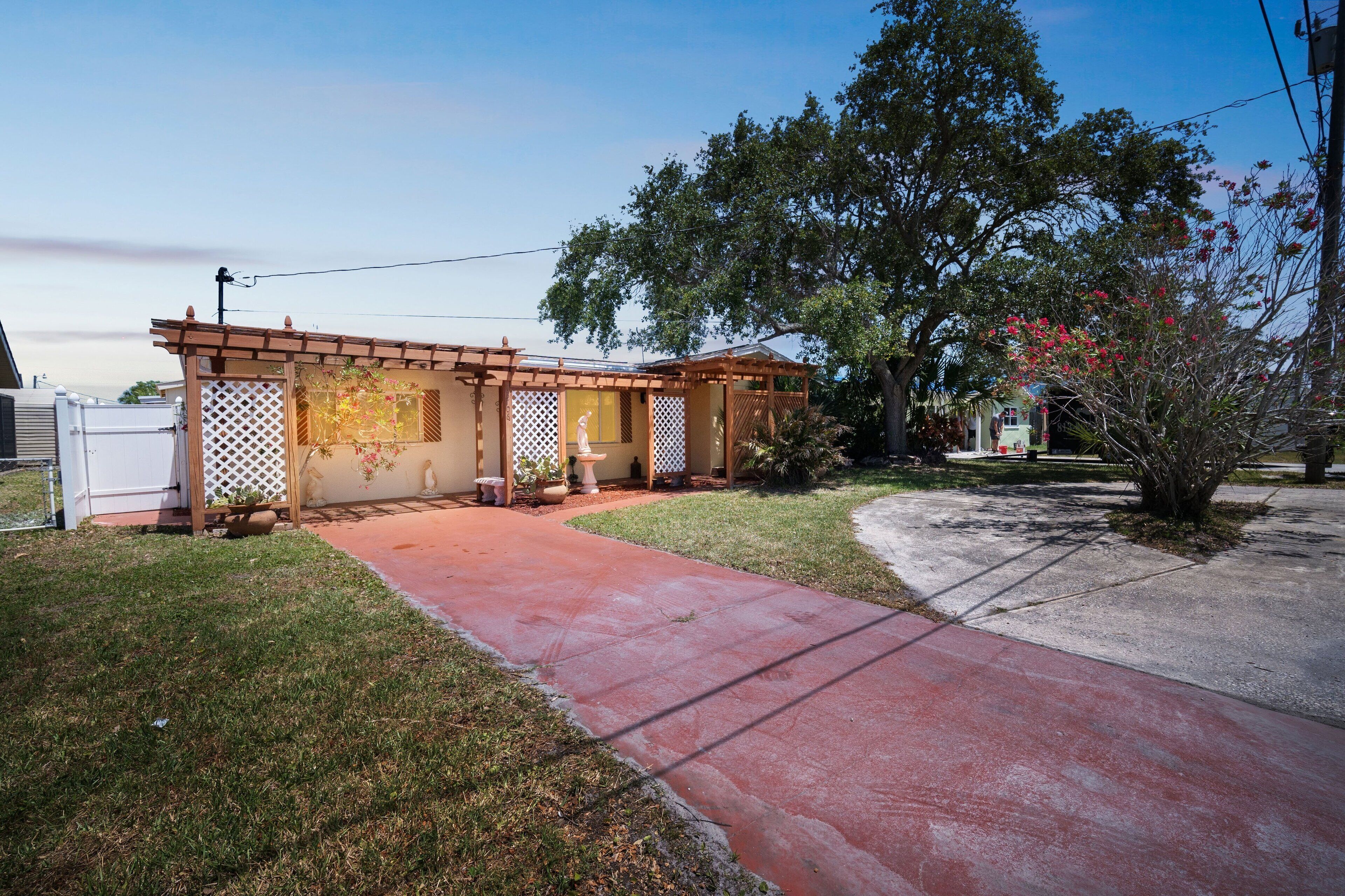 A residential property with a covered patio, a concrete driveway, and a small garden area.