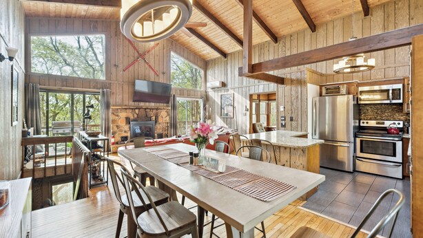A spacious kitchen with modern appliances, a dining area with a long table, and large windows offering views of the outdoors. - Charming Porter House In The Heart Of The Poconos 4 Bedroom Chalet (Bushkill)