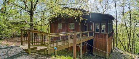 A wooden cabin with a wooden staircase and a chain-link fence.