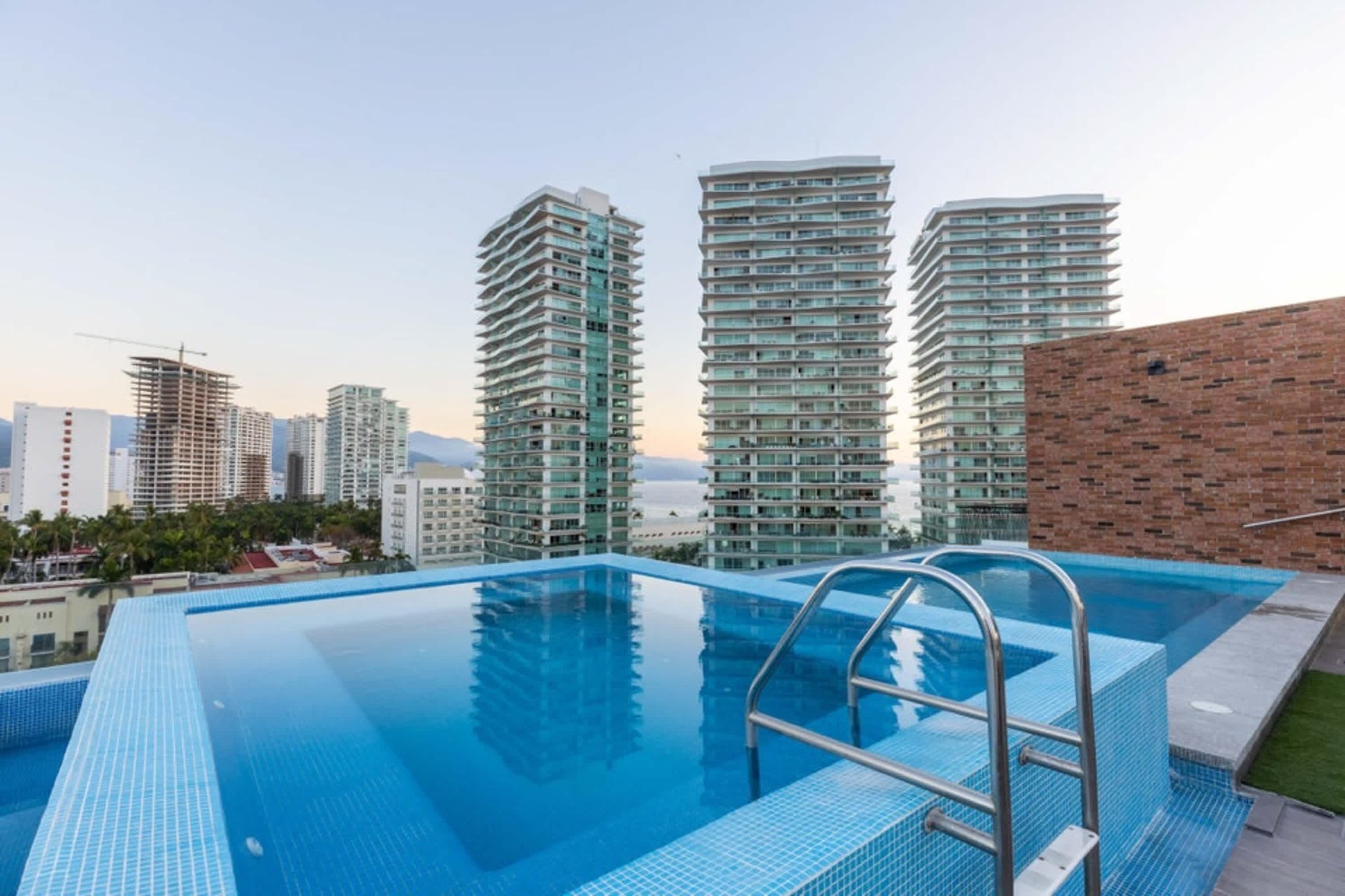 A rooftop swimming pool with a view of high-rise buildings.