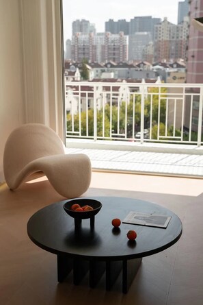 Enjoy a city view from the large window in this stylish room, featuring a round table and a sculptural chair.