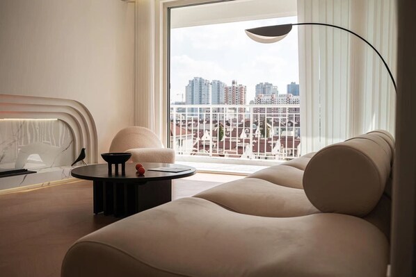 Relax in a stylish living room with a city view, featuring a curved sofa, coffee table, and floor lamp.