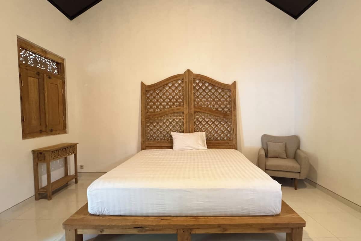 A bedroom with a wooden bed frame, a nightstand, a chair, and a decorative wooden panel on the wall.