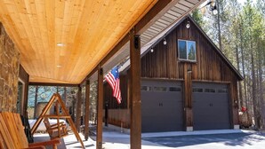 Eine Holzhütte mit überdachter Veranda, einer amerikanischen Flagge und einer Garage.