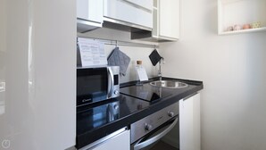 Cucina con forno a microonde, fornello, lavello e bollitore appeso.