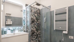 Une salle de bain avec une douche à parois de verre, un lavabo blanc et un porte-serviettes.