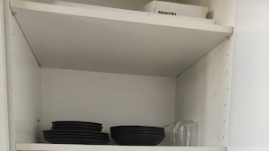 A white shelving unit with black plates, red cups, clear glasses, and a green folder. - Citrus Pop Holiday home in Piazza del Popolo (Roma)
