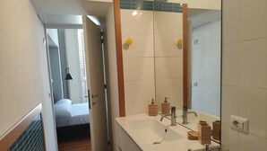 A narrow hallway leading to a bathroom with a large mirror, a sink, and wooden soap dispensers. - Citrus Pop Holiday home in Piazza del Popolo (Roma)