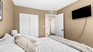 A bedroom with a bed, a TV mounted on the wall, and a wardrobe.