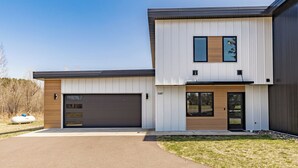 A modern two-story house with a garage, a front door, and a small porch. - Northern Comfort: The Vault - Your Refined Retreat near Duluth (Hermantown)