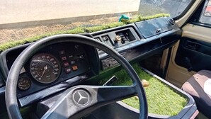 The interior of a vehicle with a steering wheel, dashboard, and gear shift. - Vintage Camper Van in Mallorca, with everything for live, 9 persons driving. (Sol de Mallorca)