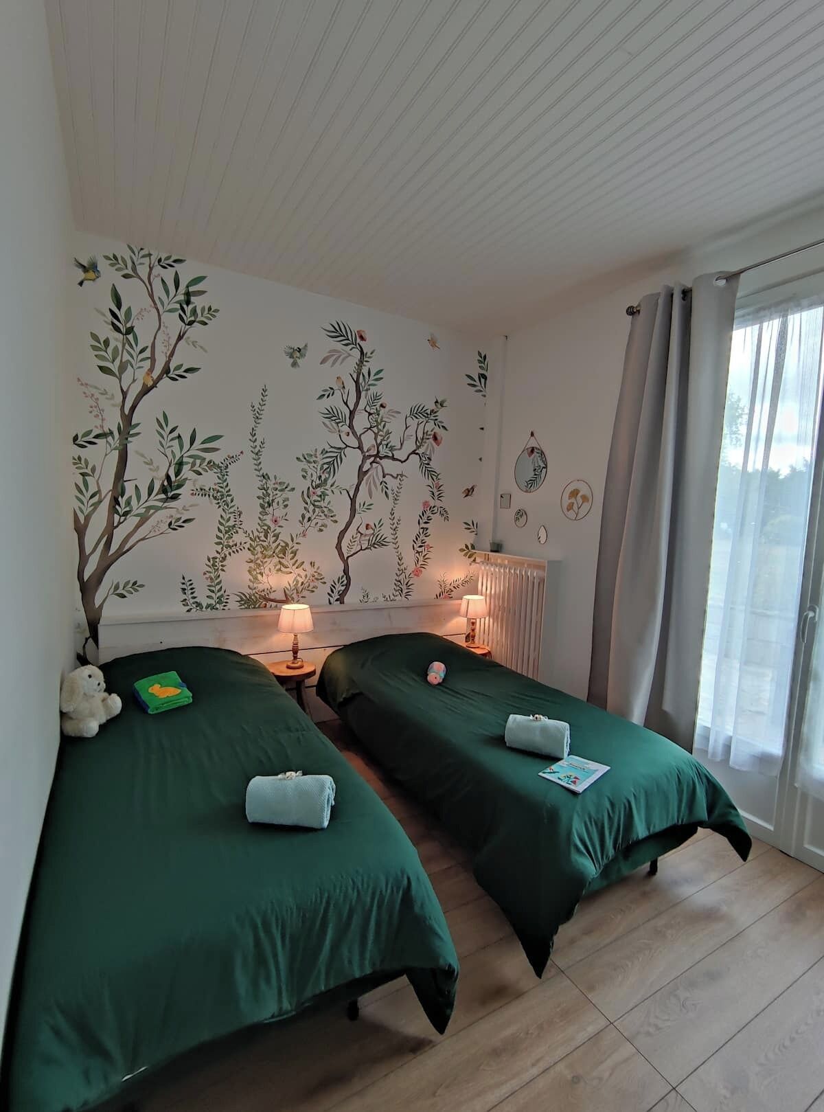 Ein Hotelzimmer mit zwei Einzelbetten, einer Wandmalerei, einem Fenster mit Vorhängen und einem Holzboden.