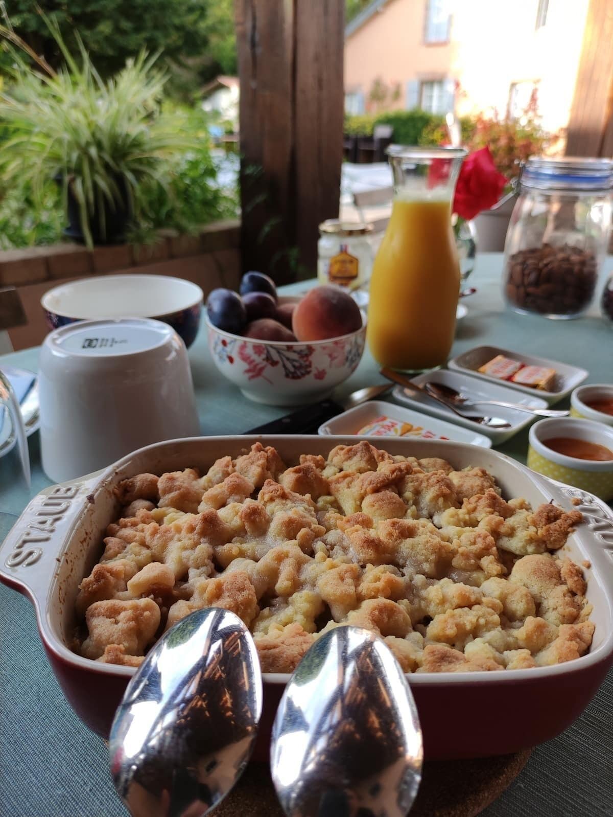 Een eettafel met een ovenschotel, een fruitschaal en een glas jus d'orange.