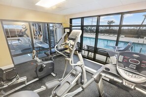 A gym with cardio machines, weight equipment, and a view of a pool through large windows. - Grand Pointe 310, panoramic views, huge balcony, 3rd floor with 3 bedrooms, 3.5 baths (Orange Beach)