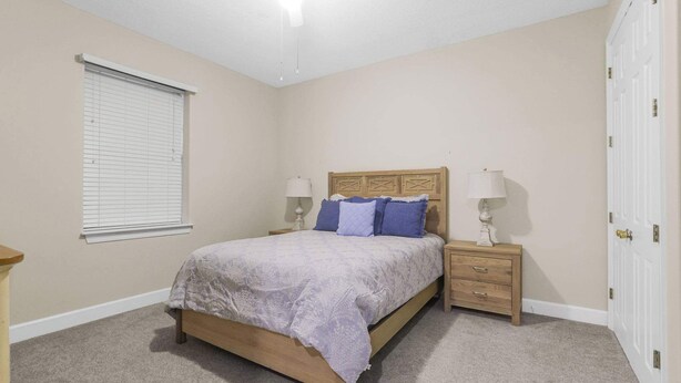 A bedroom with a bed, two bedside tables, a window with blinds, and a door. - Grand Pointe 310, panoramic views, huge balcony, 3rd floor with 3 bedrooms, 3.5 baths (Orange Beach)