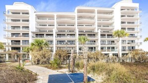 A multi-story hotel with balconies, a wooden boardwalk, and surrounding vegetation. - Grand Pointe 310, panoramic views, huge balcony, 3rd floor with 3 bedrooms, 3.5 baths (Orange Beach)