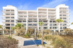 A multi-story hotel with balconies, a wooden boardwalk, and surrounding vegetation.