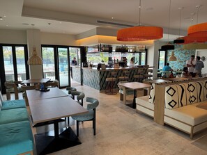 A modern cafe with a bar area, seating arrangements, and large windows.