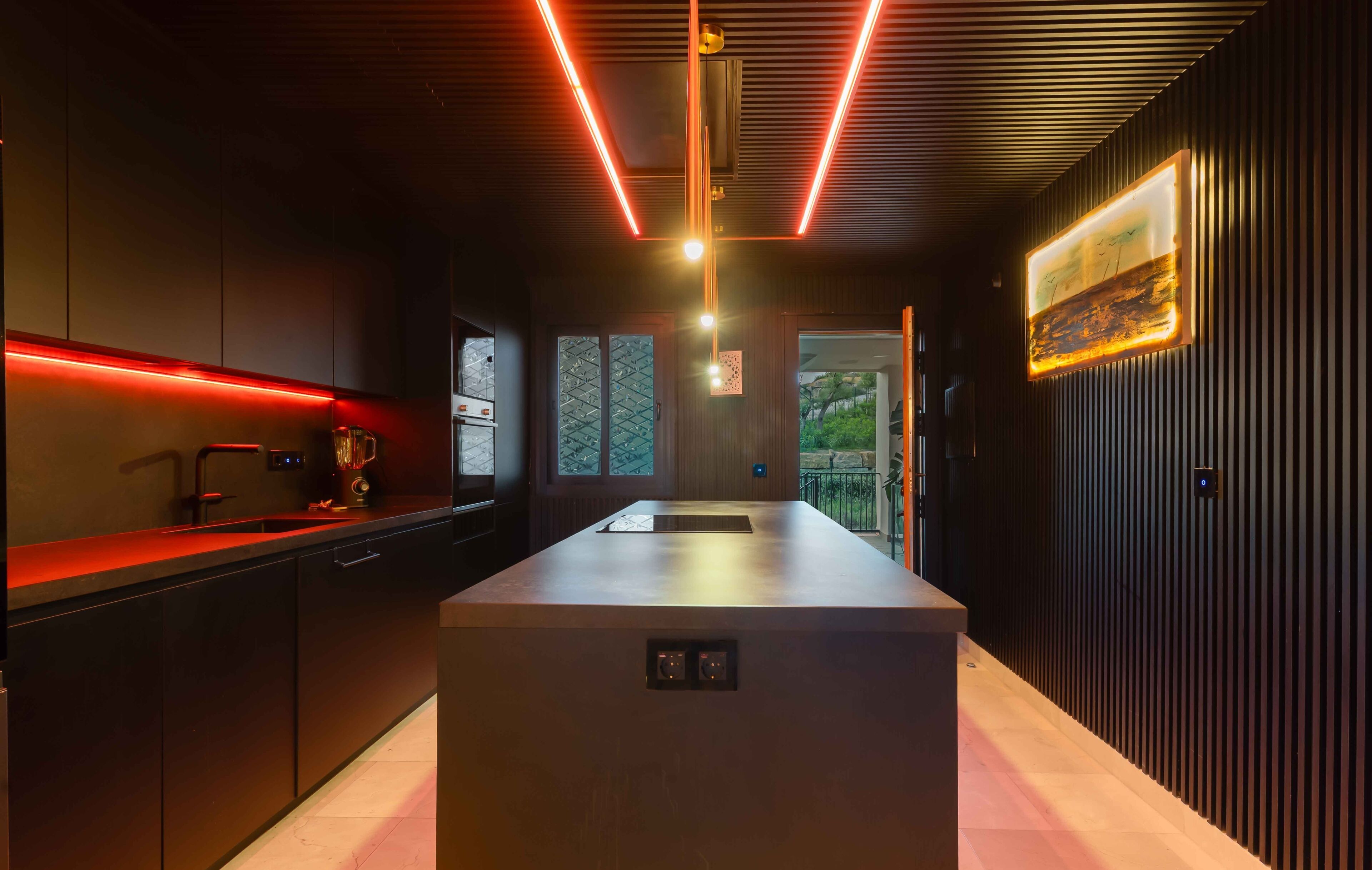 A modern kitchen with a central island, wooden paneling, and a view of the outdoors.