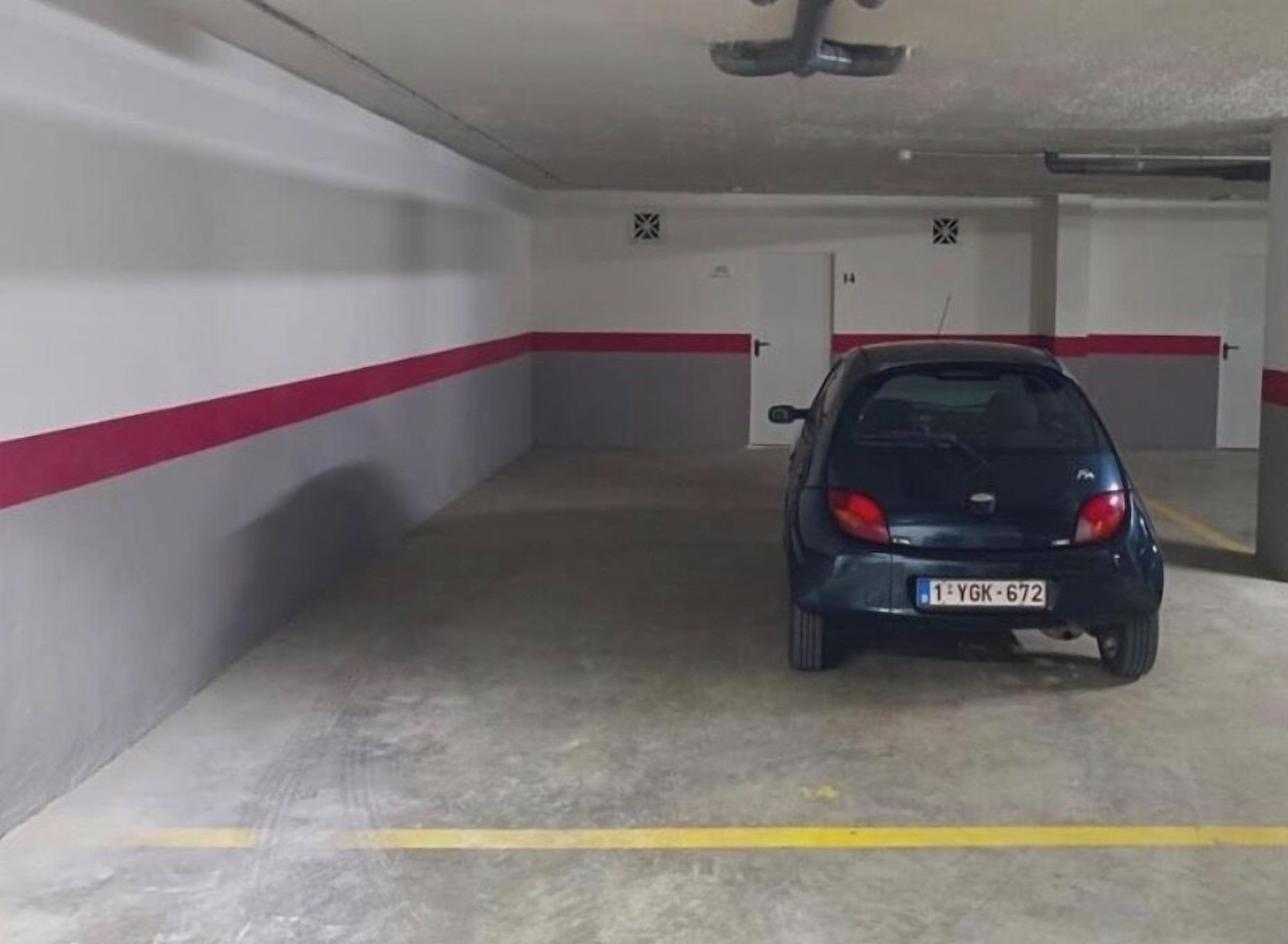 Un parcheggio sotterraneo con un'auto parcheggiata in un posto delimitato da una linea gialla.
