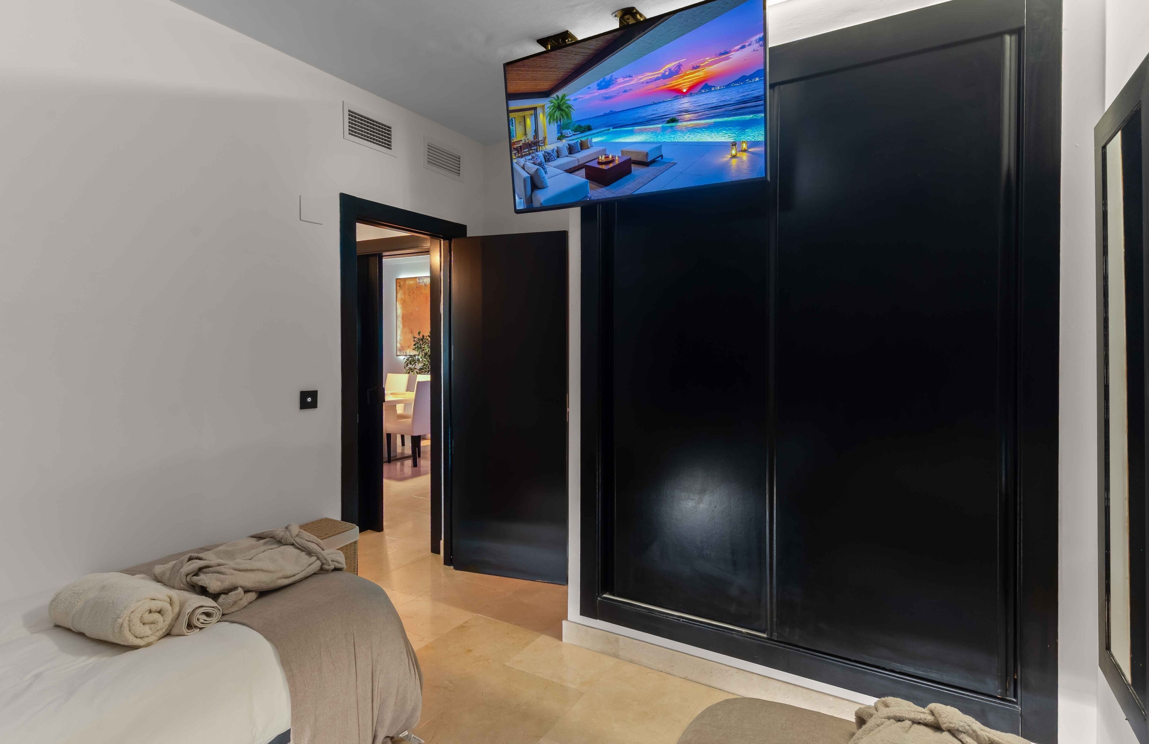 A hotel room with a bed, a TV mounted on the wall, and a view of a pool.