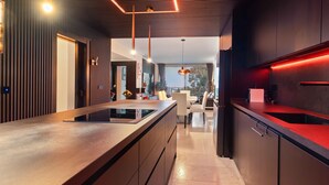 A modern kitchen with a central island, built-in appliances, and a dining area with a view. - Al Fattah Luxury (Estepona)