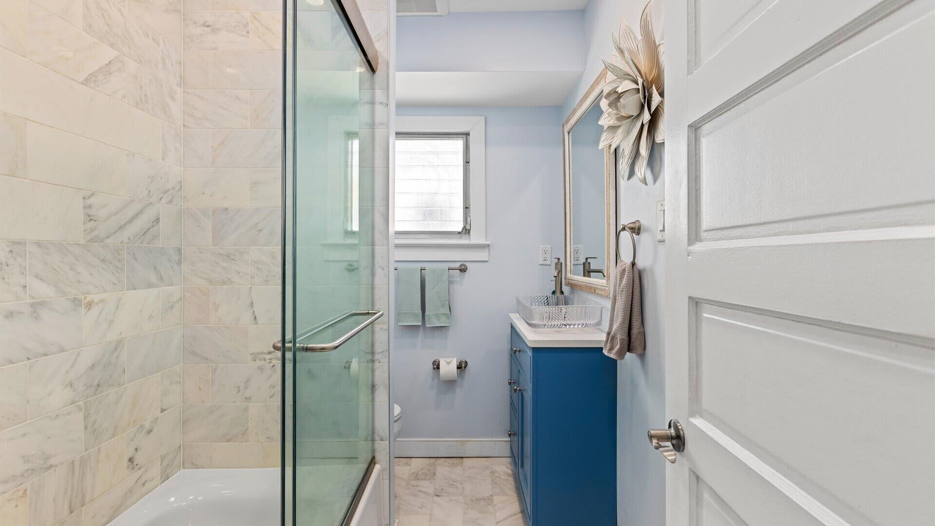 Une salle de bain avec une douche à parois de verre, des toilettes, un lavabo avec un miroir et un porte-serviettes.