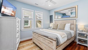 A bedroom with a bed, a dresser, a mirror, and a television.