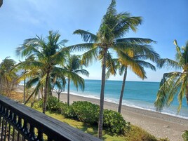 Una playa con palmeras y una barandilla de madera.