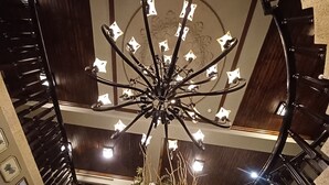 A grand staircase with a chandelier and floral arrangement at the top. - Jasmine Bay (Fangshan)