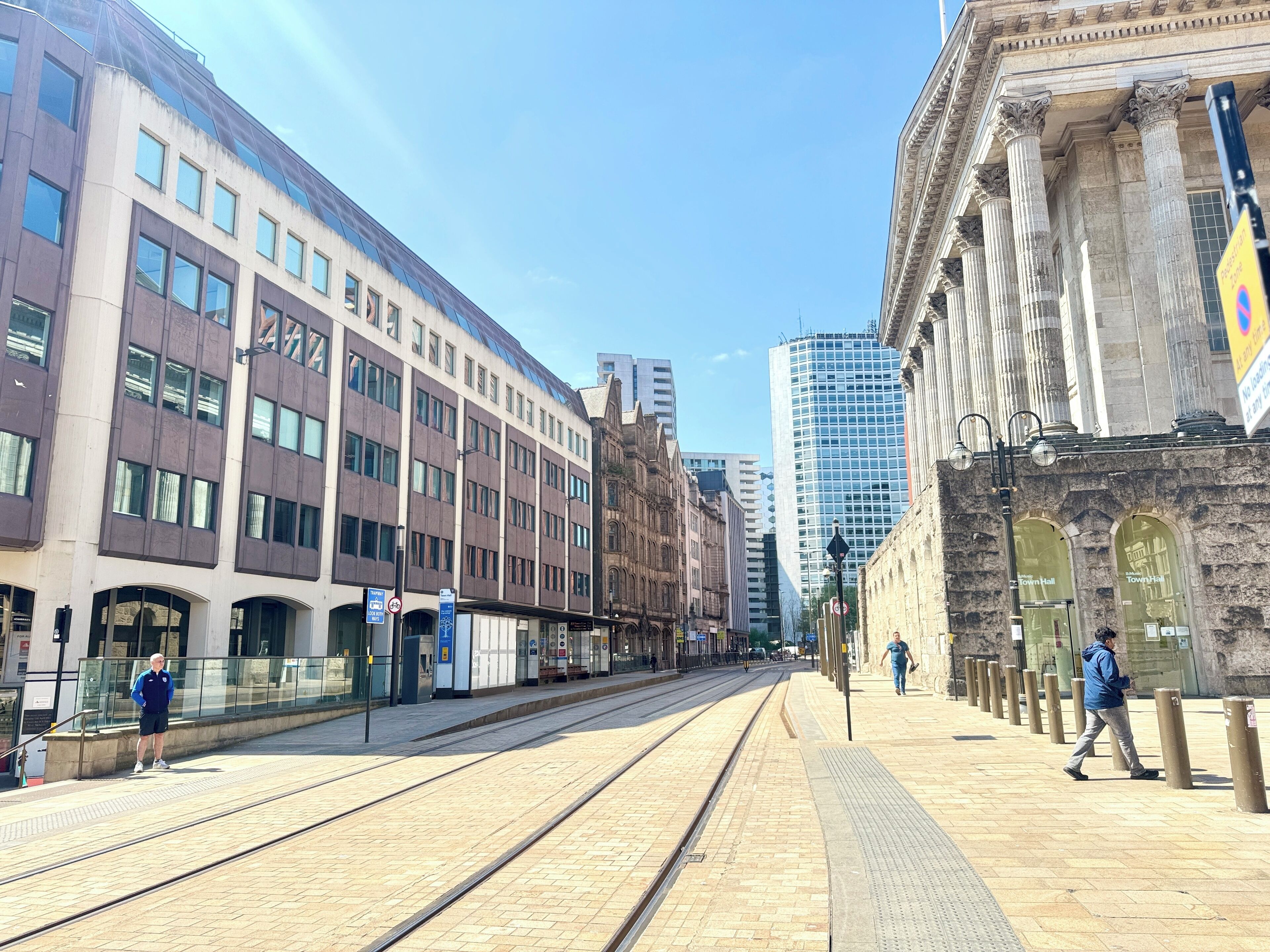 Una calle urbana con tranvías, edificios históricos y arquitectura moderna.