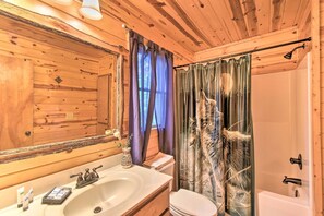 Ein Badezimmer einer Holzhütte mit Waschbecken, Toilette und Dusche.