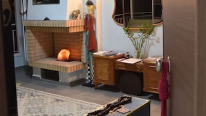 Una habitación con chimenea, espejo, escritorio y alfombra.