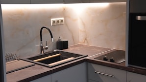 Una cocina moderna con salpicadero de mármol, electrodomésticos de acero inoxidable y un lavamanos empotrado.