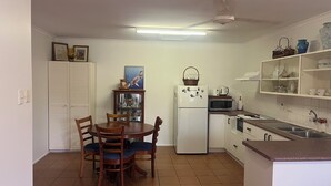 A compact kitchen with a dining area, white cabinets, a refrigerator, microwave, and a sink. - Bongaree Getaway, Clean Comfy, and Homely. (Bongaree)